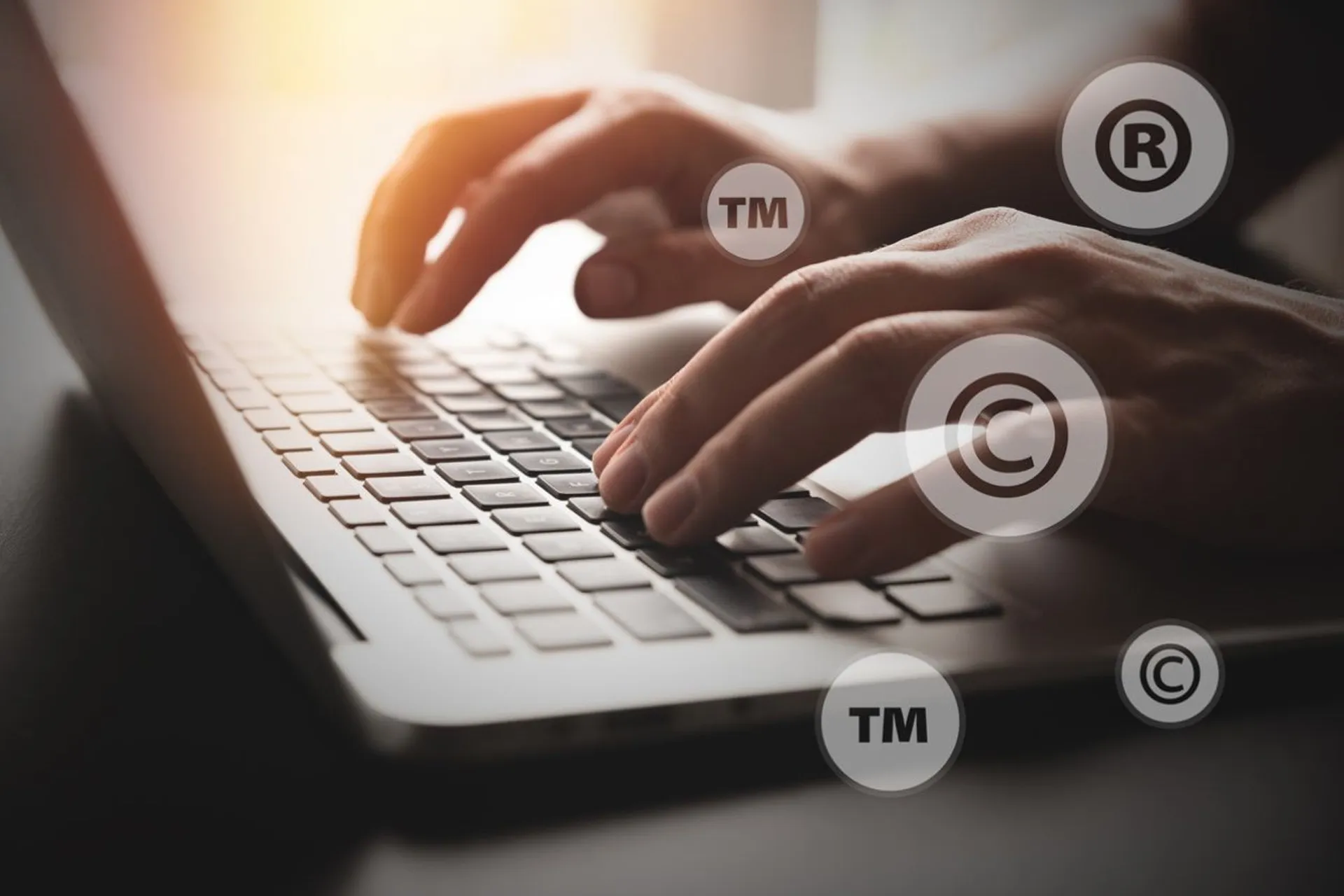 Hands typing on a laptop with trademark and copyright symbols